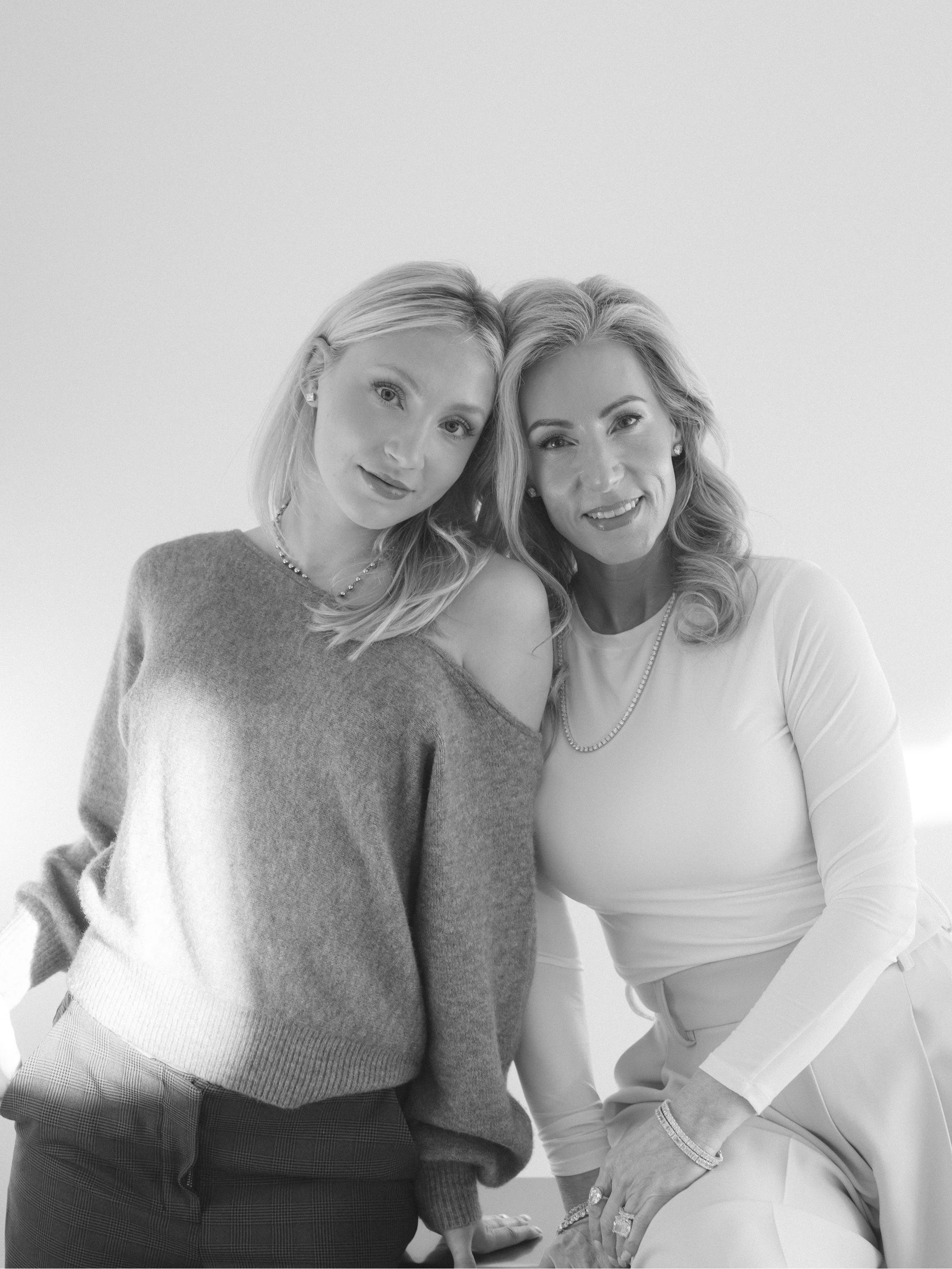 Two women posing together against a white background